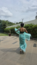 Sea green chiffon saree with white leaf print, model walking outdoors Back side waking away