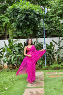 Pink chiffon leheriya saree with gold border, model posing outdoors, showing saree