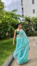 Sea green chiffon saree with white leaf print, model posing outdoors