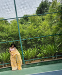 Sea green chiffon saree with white leaf print, model posing outdoors beneath 