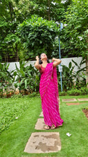 Pink chiffon leheriya saree with gold border, model posing outdoors In garden
