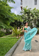 Sea green chiffon saree with white leaf print, model walking outdoors In garden side