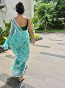 Sea green chiffon saree with white leaf print, model walking outdoors Pathway