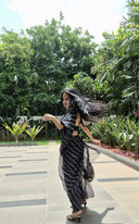 Black chiffon leheriya saree with gold border, model walking outdoors