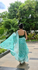 Sea green chiffon saree with white leaf print, model walking outdoors Back view