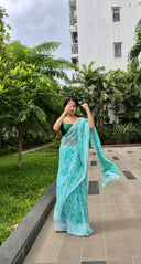 Sea green chiffon saree with white leaf print, model walking outdoors Front view