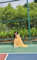 Sea green chiffon saree with white leaf print, model sitting outdoors