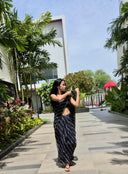 Black chiffon leheriya saree with gold border, model in outdoors