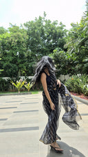 Black chiffon leheriya saree with gold border, model posing outdoors
