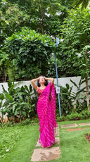 Pink chiffon leheriya saree with gold border, model posing outdoors